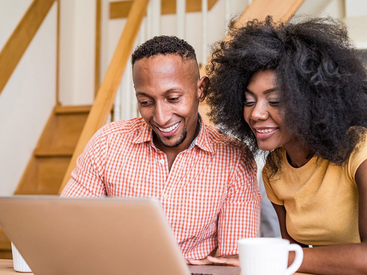 Young couple in kitchen looking at a laptop together