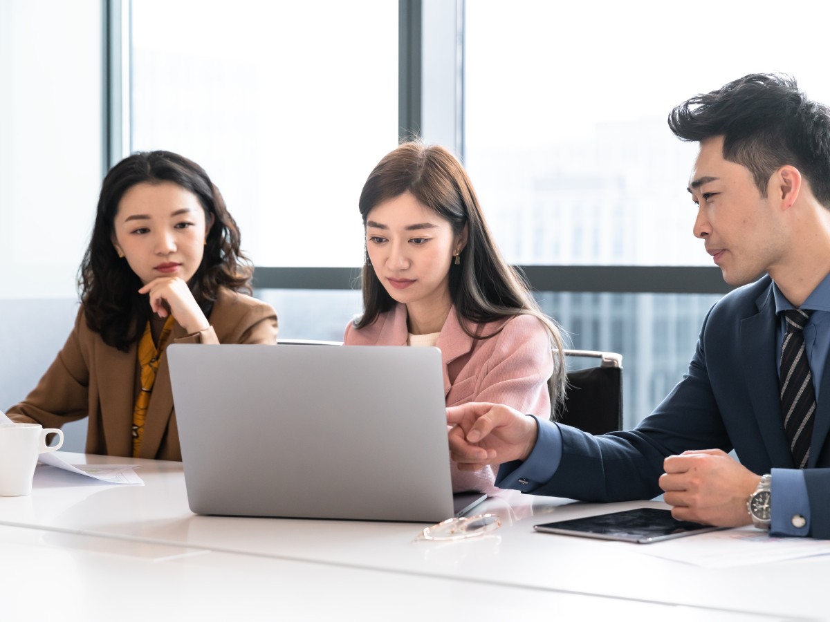 Three young Asian people with laptop at a meeting or seminar