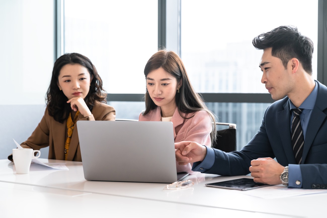 Three young Asian people with laptop at a meeting or seminar