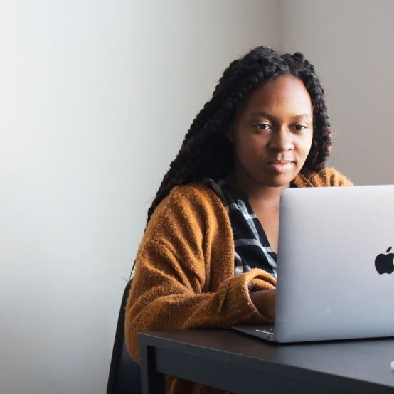 Black woman at desk in front of Mac laptop