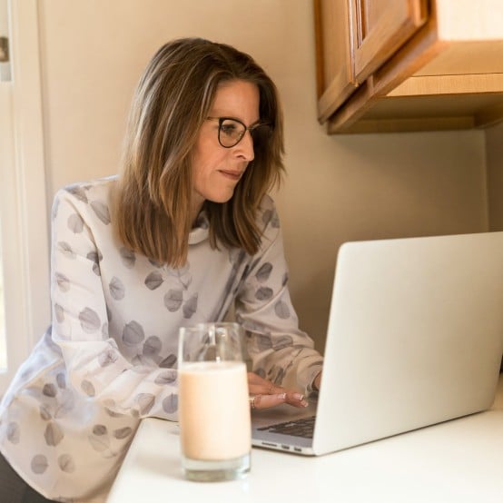 Middle-aged woman using laptop in kitchen